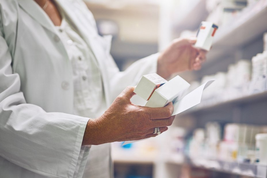 Apothekerin holt die im Rezept aufgeführten Medikamente aus einem Regal