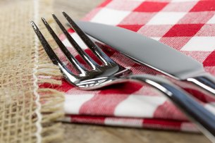 Es liegen Gabel und Messer auf einer rot-weiß karierten Serviette
