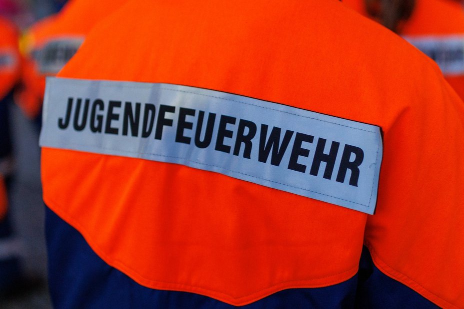 Feuerwehrler in Arbeitsjacke mit dem Aufdruck "Jugendfeuerwehr", von hinten fotografiert